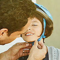 Father putting a bike helmet on his child.