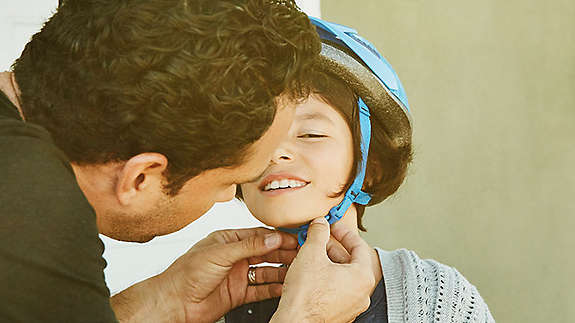 Father putting a bike helmet on his child.