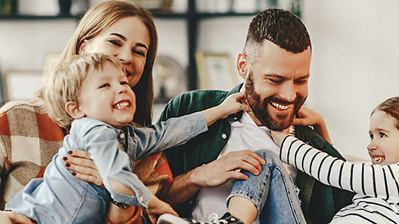 A family laughing and playing together on a sofa