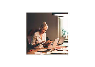 woman doing work with a tablet and laptop at home