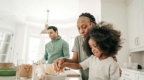 Mom helping child with food dad in background