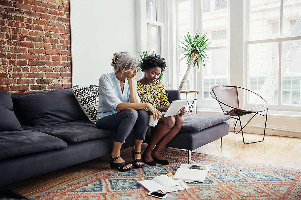 Mother and daughter on couch looking at a computer.