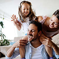 Two adults and a child playing in a well-lit room