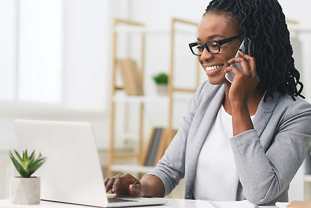 Person working on laptop and talking on the phone